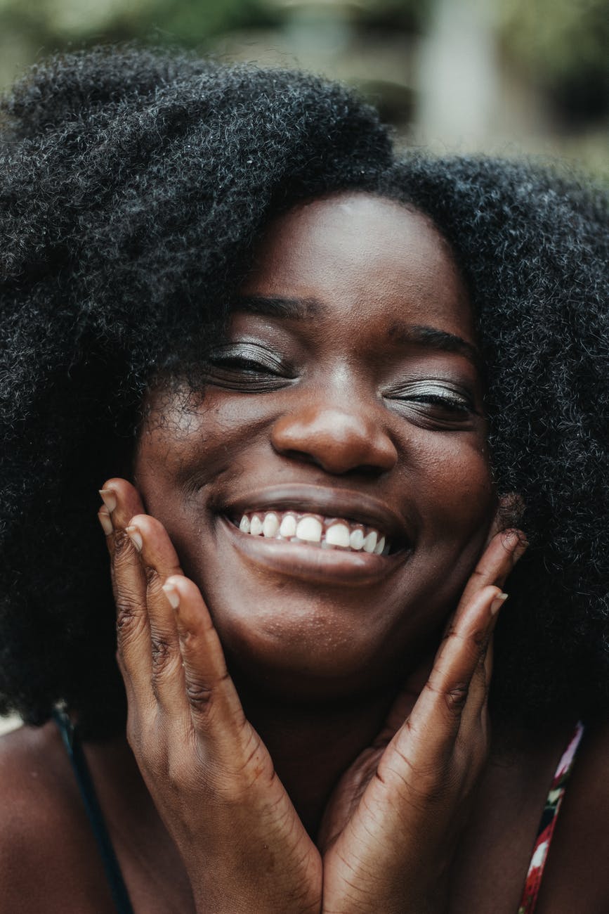 delighted black woman touching cheeks