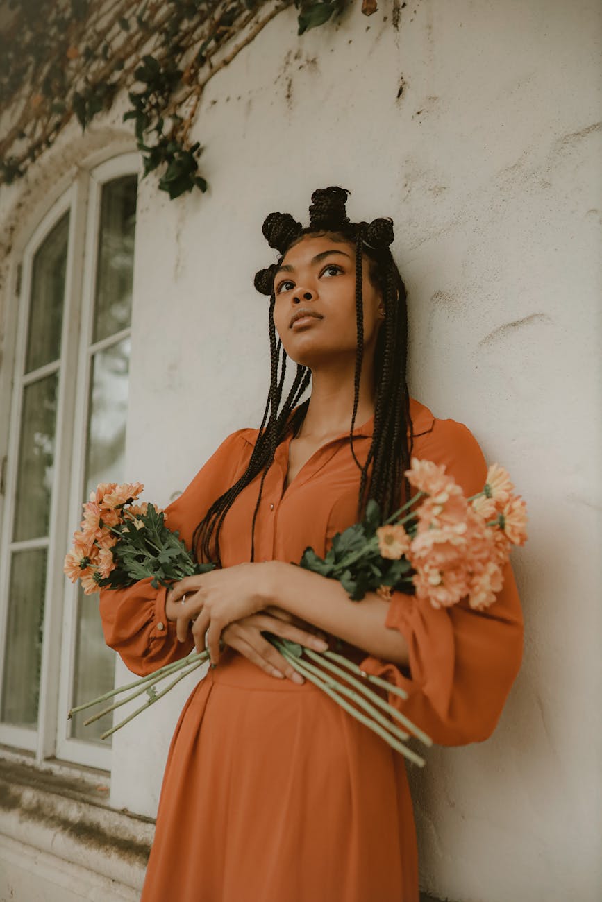 woman holding bouquet of flowers leaning against wall