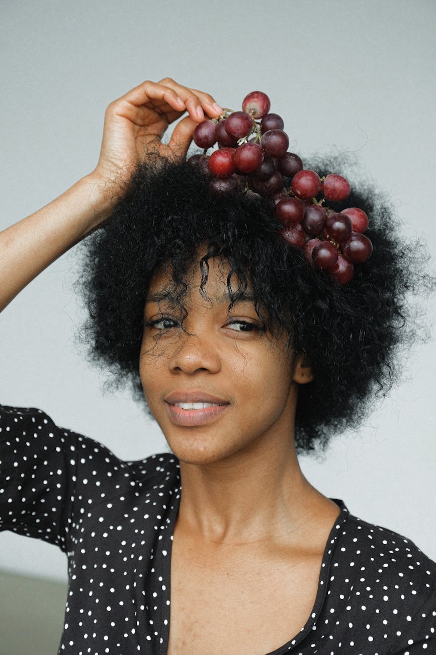 woman in black and white polka dot shirt holding red round fruit