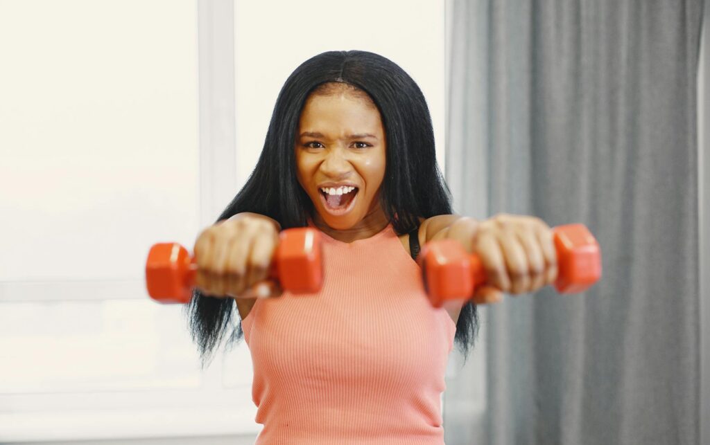 woman holding red dumbbells