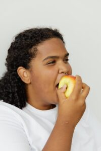 woman in white crew neck shirt eating an apple