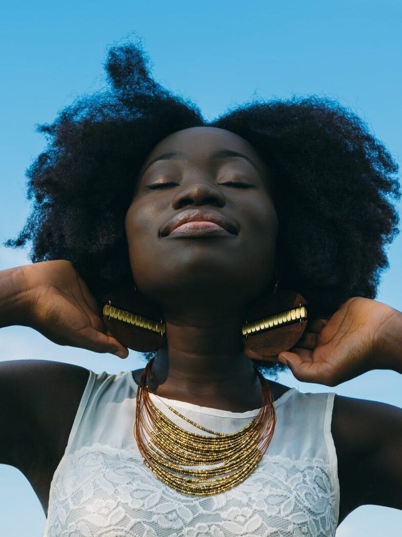 dark-skin-woman-with-beautiful-natural-hair-wearing-white-sleeveless-lace-shirt.